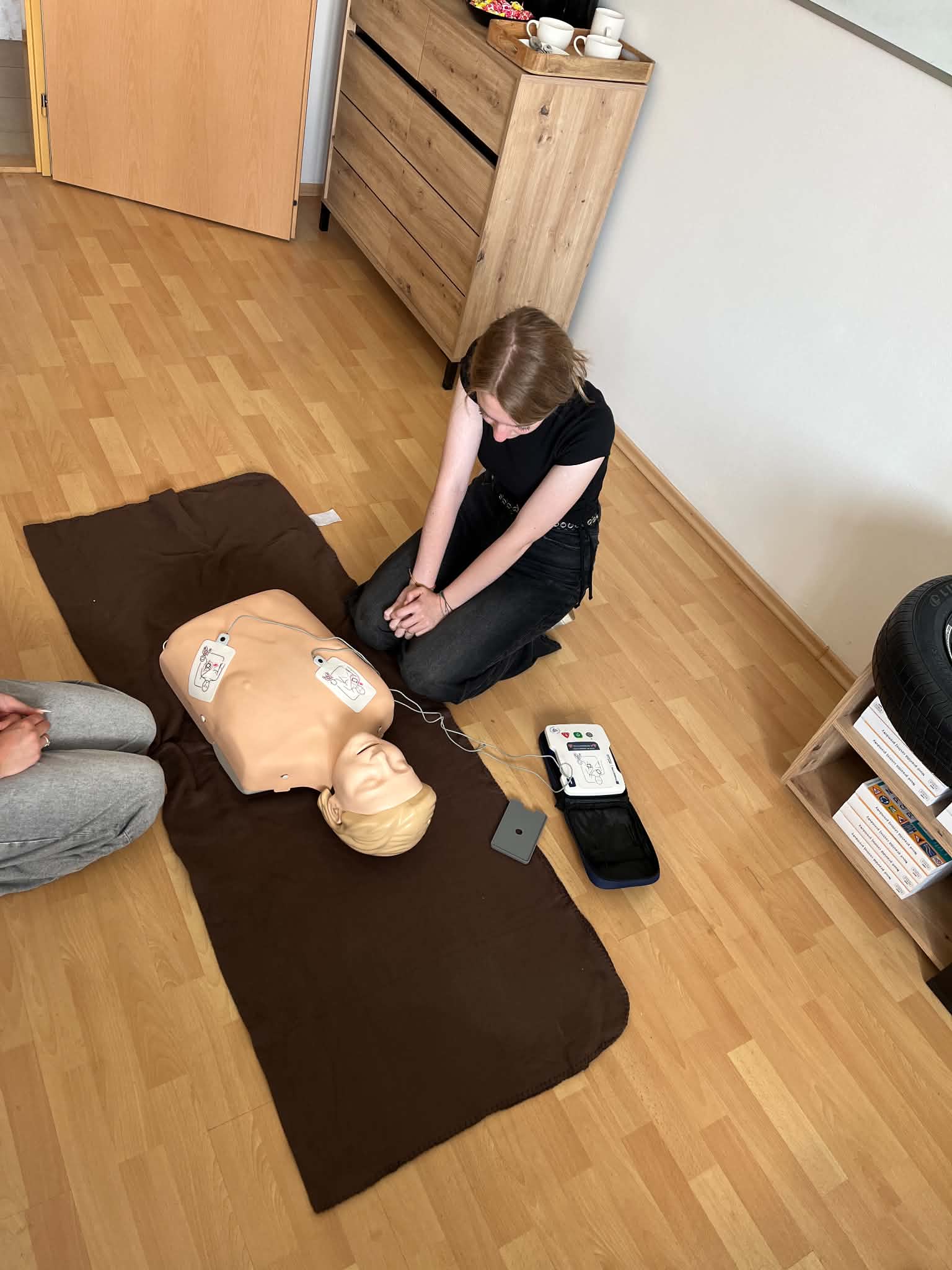 Ruky nalepujú elektródy defibrilátora AED na cvičnú figurínu