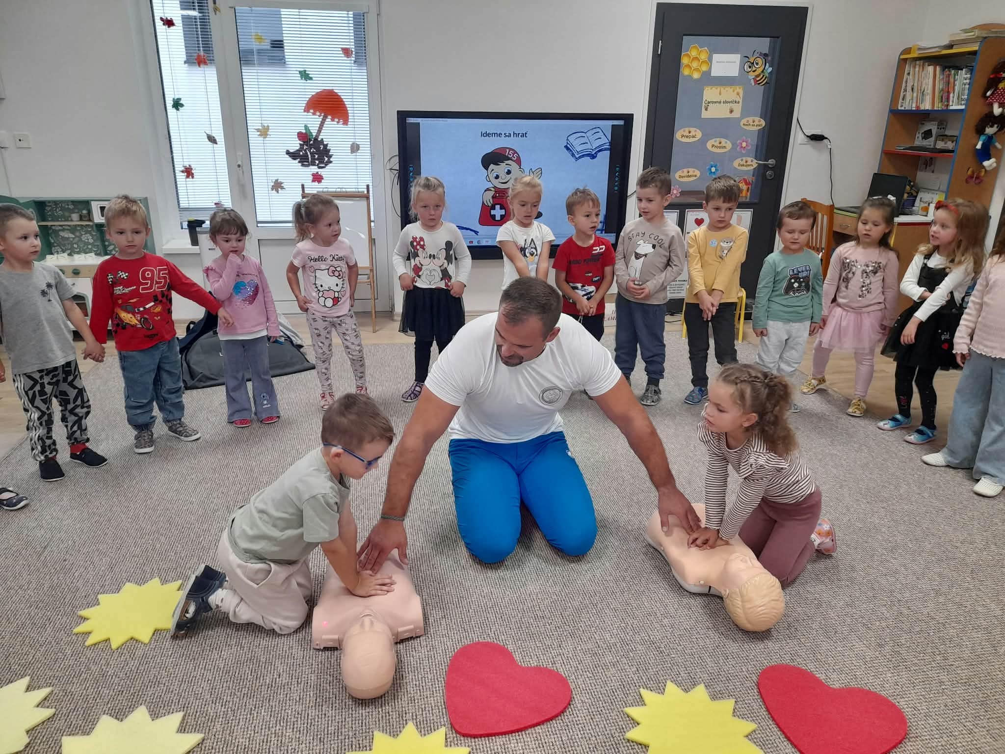 Žiaci si na podlahe skúšajú stláčanie hrudníka na figurínach